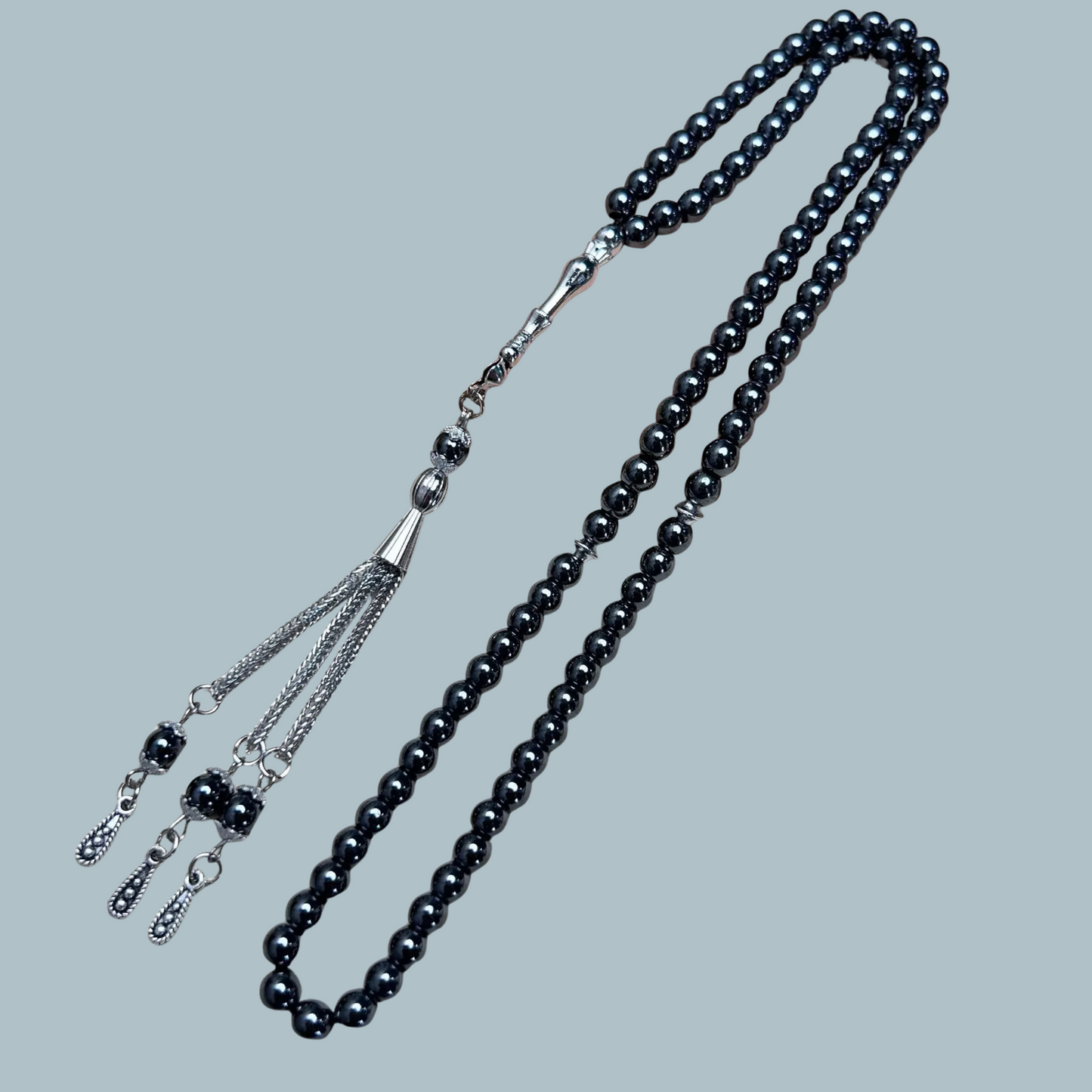 99-bead Hematite tasbih with metallic sheen and metal tassel on display