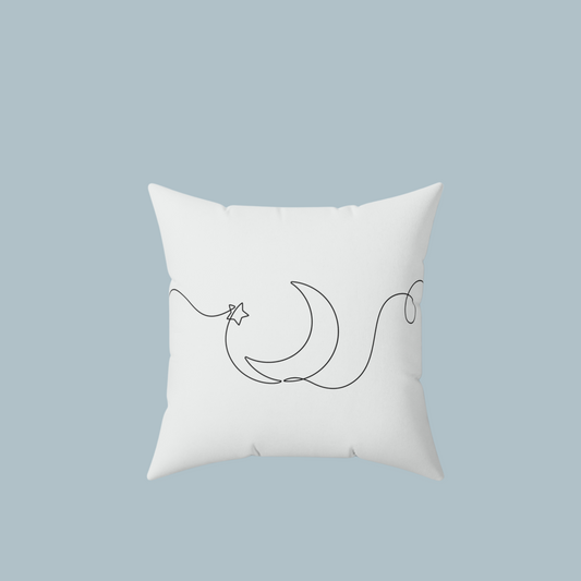 White pillow with black crescent moon and star design on a light blue background