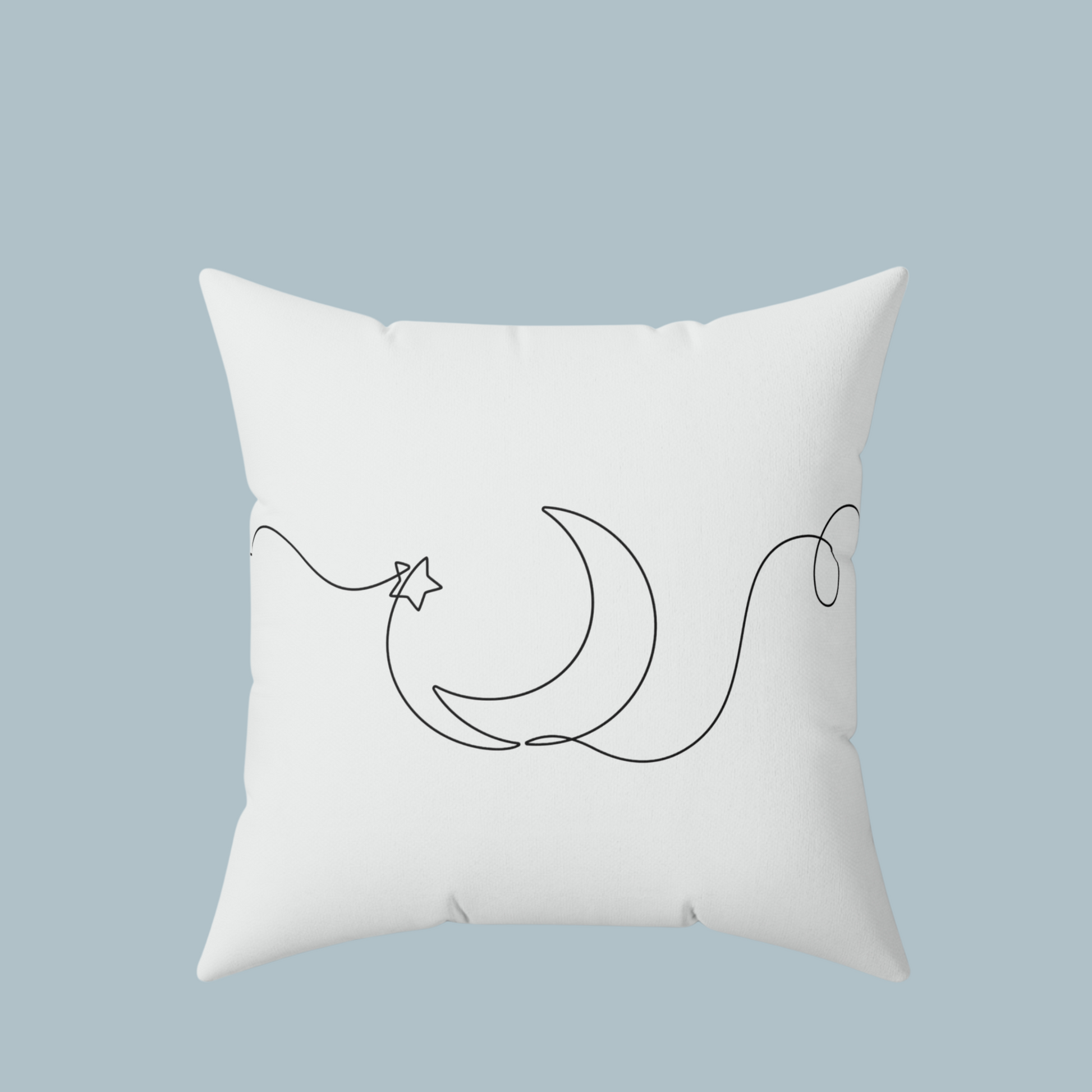 White pillow with black crescent moon and star design on a light blue background