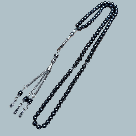 99-bead Hematite tasbih with metallic sheen and metal tassel on display