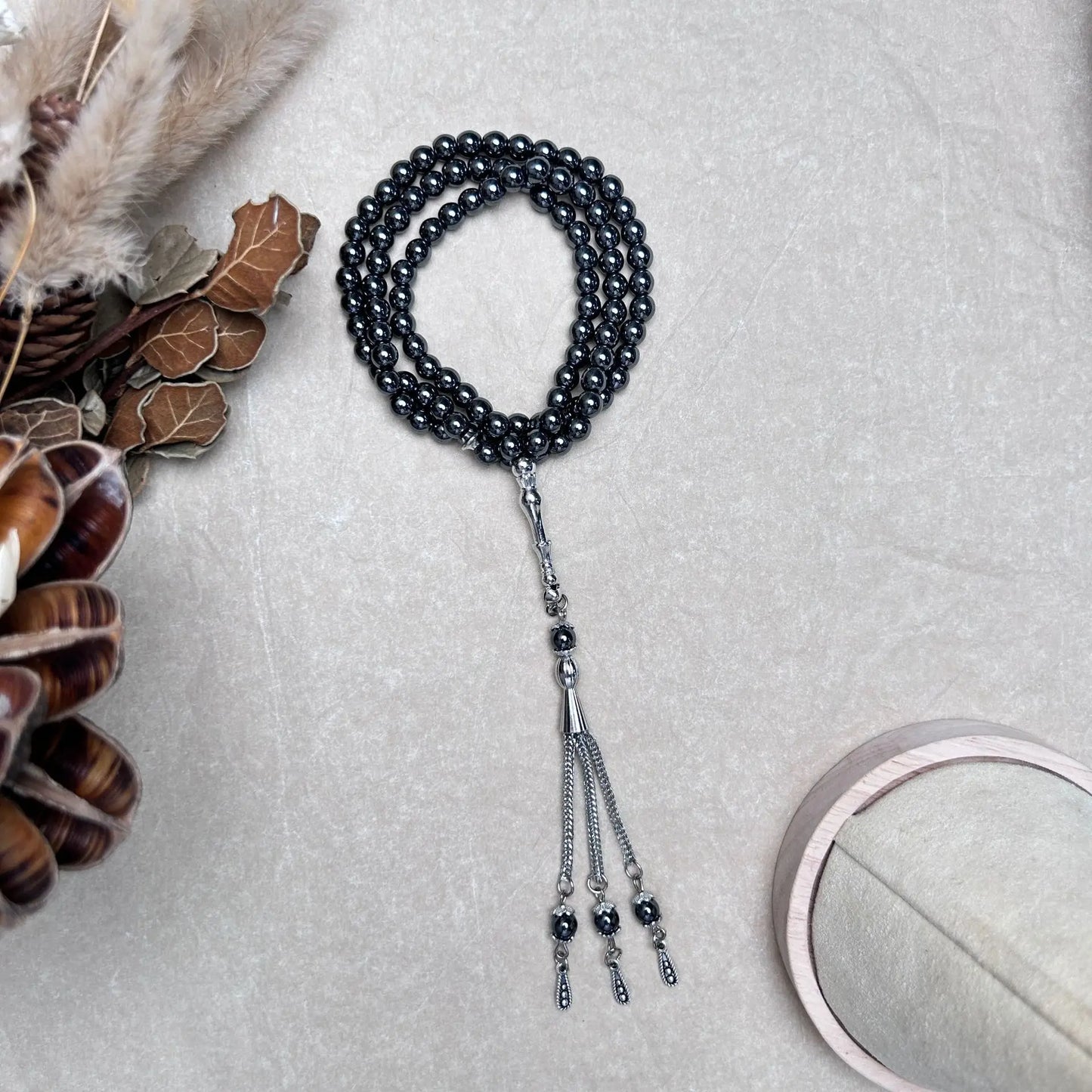 99-bead Hematite tasbih with metal tassel arranged in curved layout