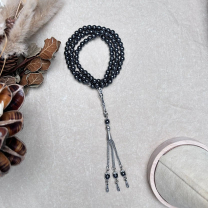 99-bead Hematite tasbih with metal tassel arranged in curved layout