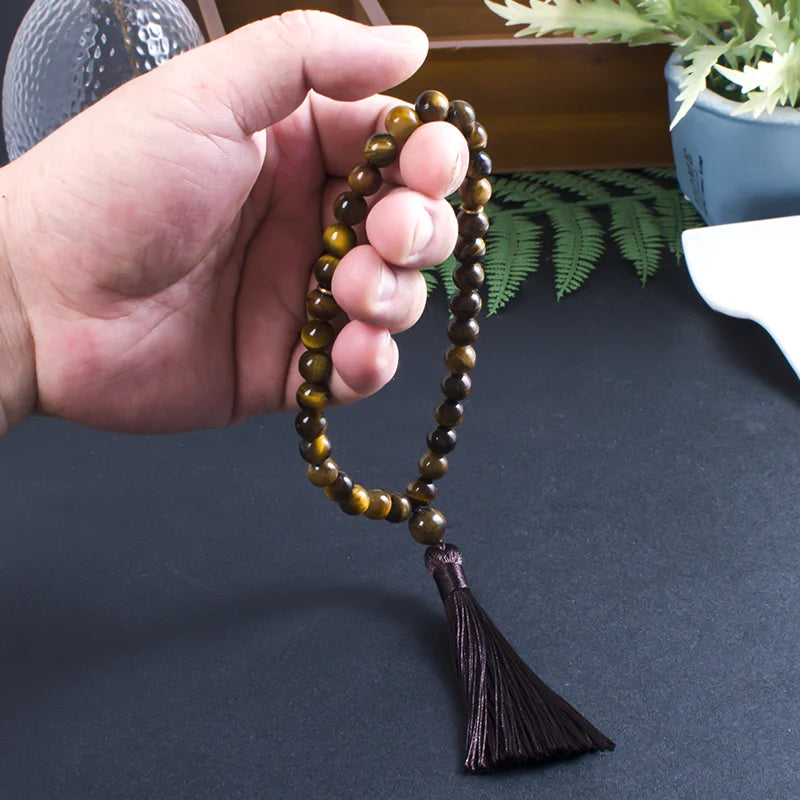 33-bead Tiger Eye tasbih held in hand, showing bead size and tassel