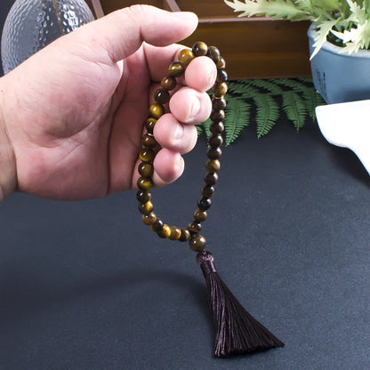 33-bead Tiger Eye tasbih held in hand, showing bead size and tassel