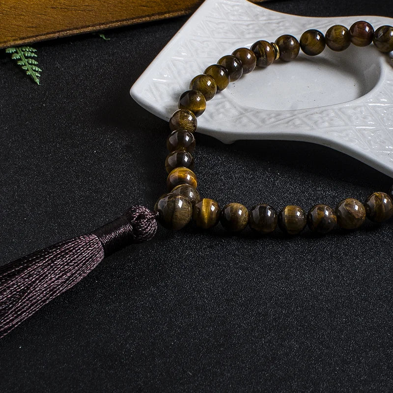 Close-up lifestyle image of 33-bead Tiger Eye tasbih showing non-knotted stringing