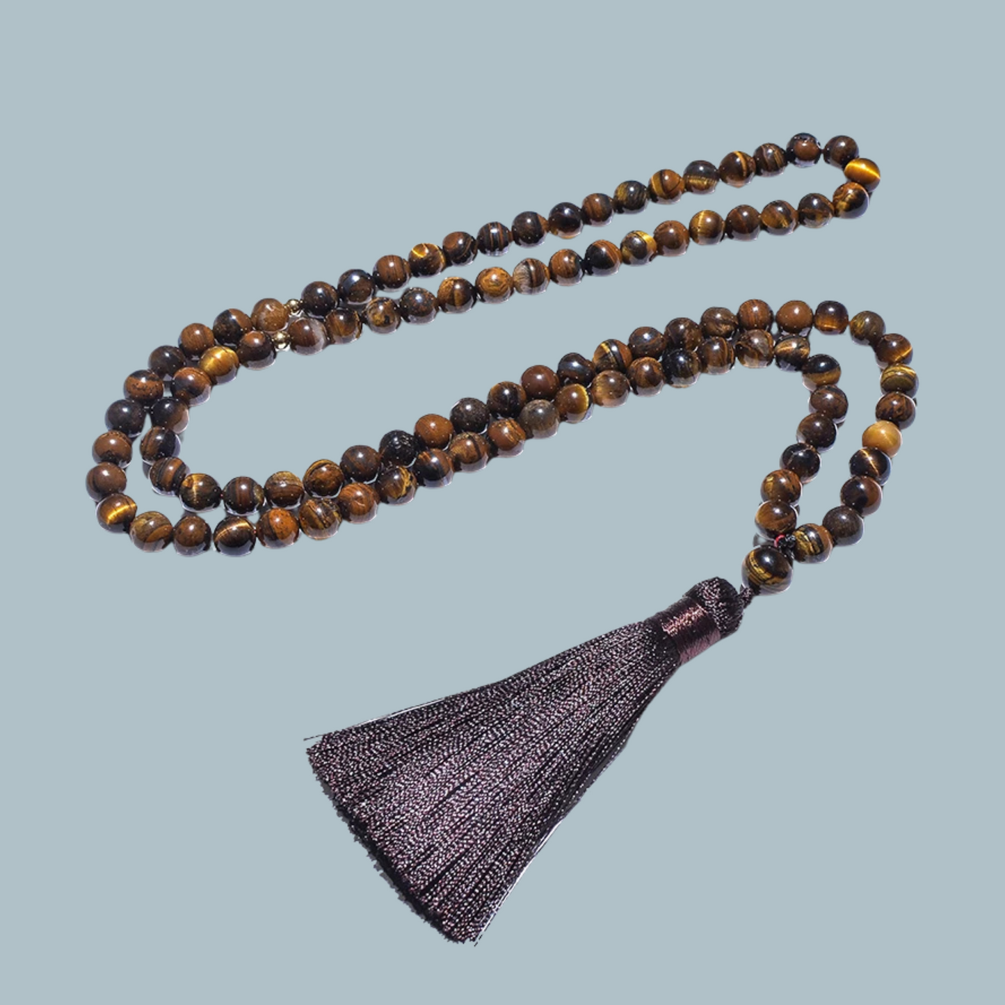 99-bead Tiger Eye tasbih laid out neatly, showcasing natural stone patterns
